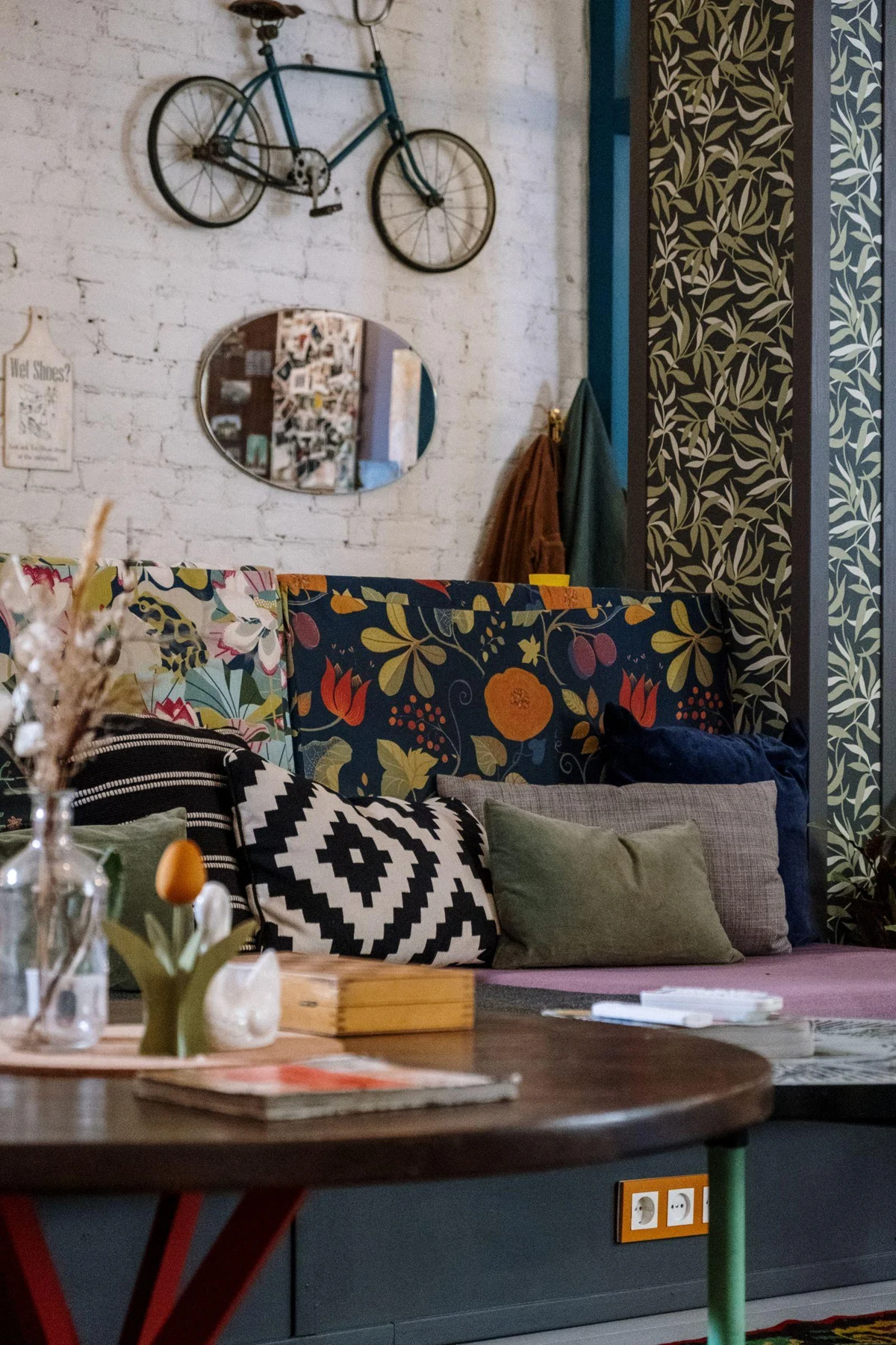 Floral upholstery, patterned cushions and decorative wall objects in a colorful living room.