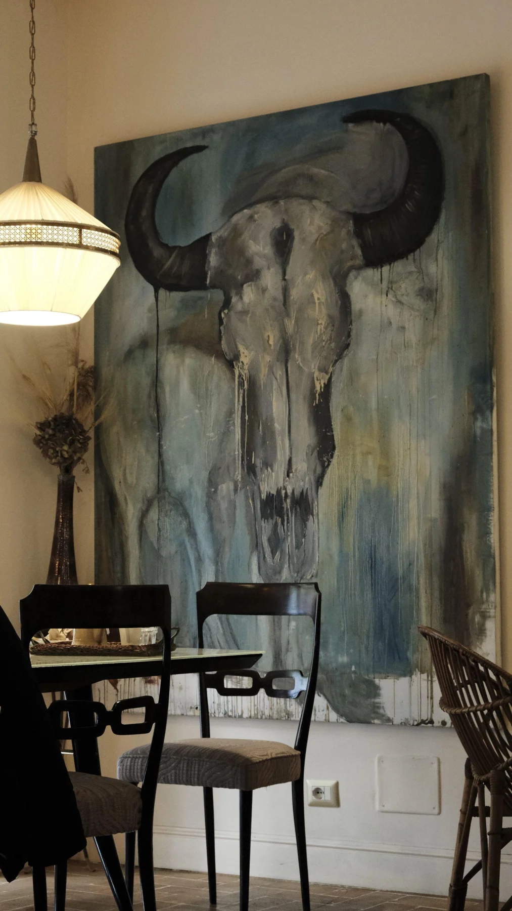 A large monochrome bull skull artwork beside dining chairs.