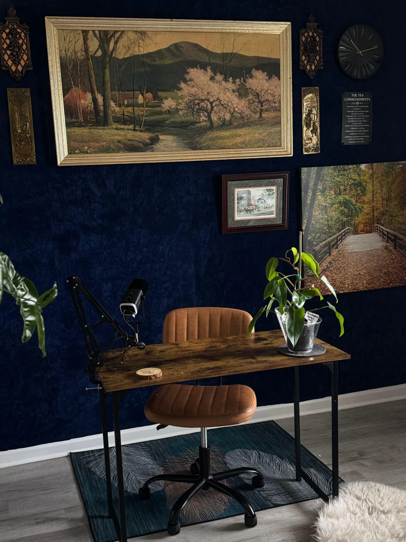 A home office desk beneath framed artworks on a navy wall.