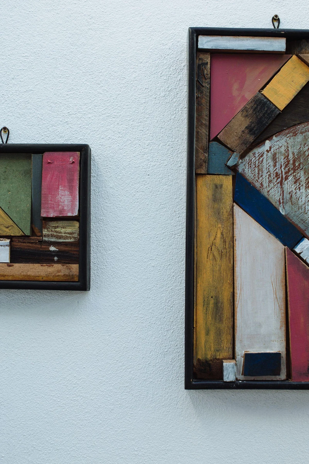 Two abstract wooden artworks combine different compositions with related colors.